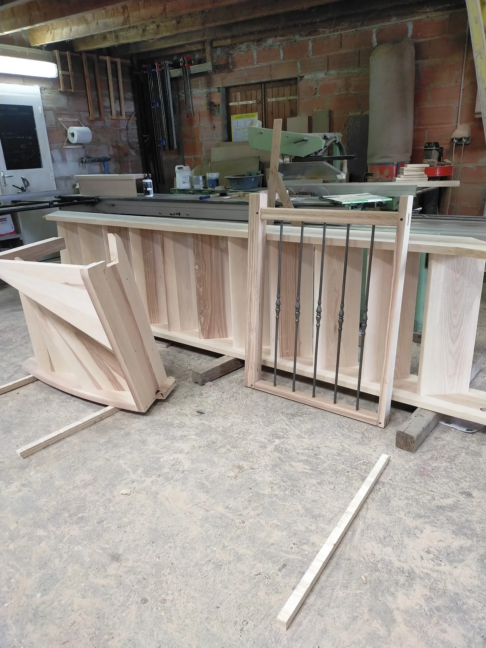 Éléments de garde-corps en bois clair et barreaux métalliques dans un atelier