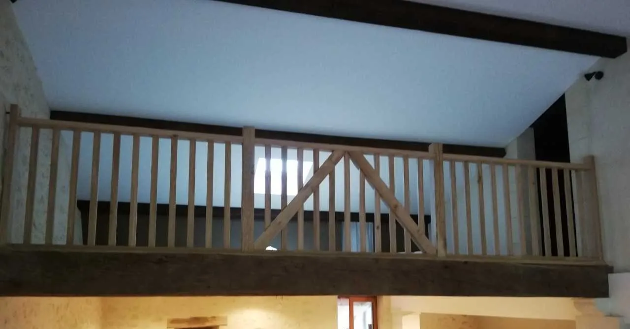 Garde-corps en bois à montants verticaux installé sur une mezzanine