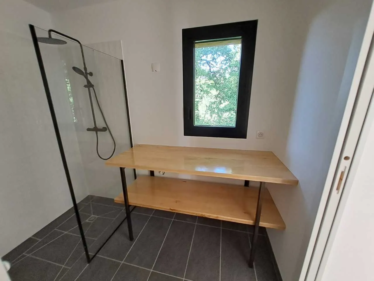 Meuble vasque en bois clair avec étagère basse dans une salle de bains