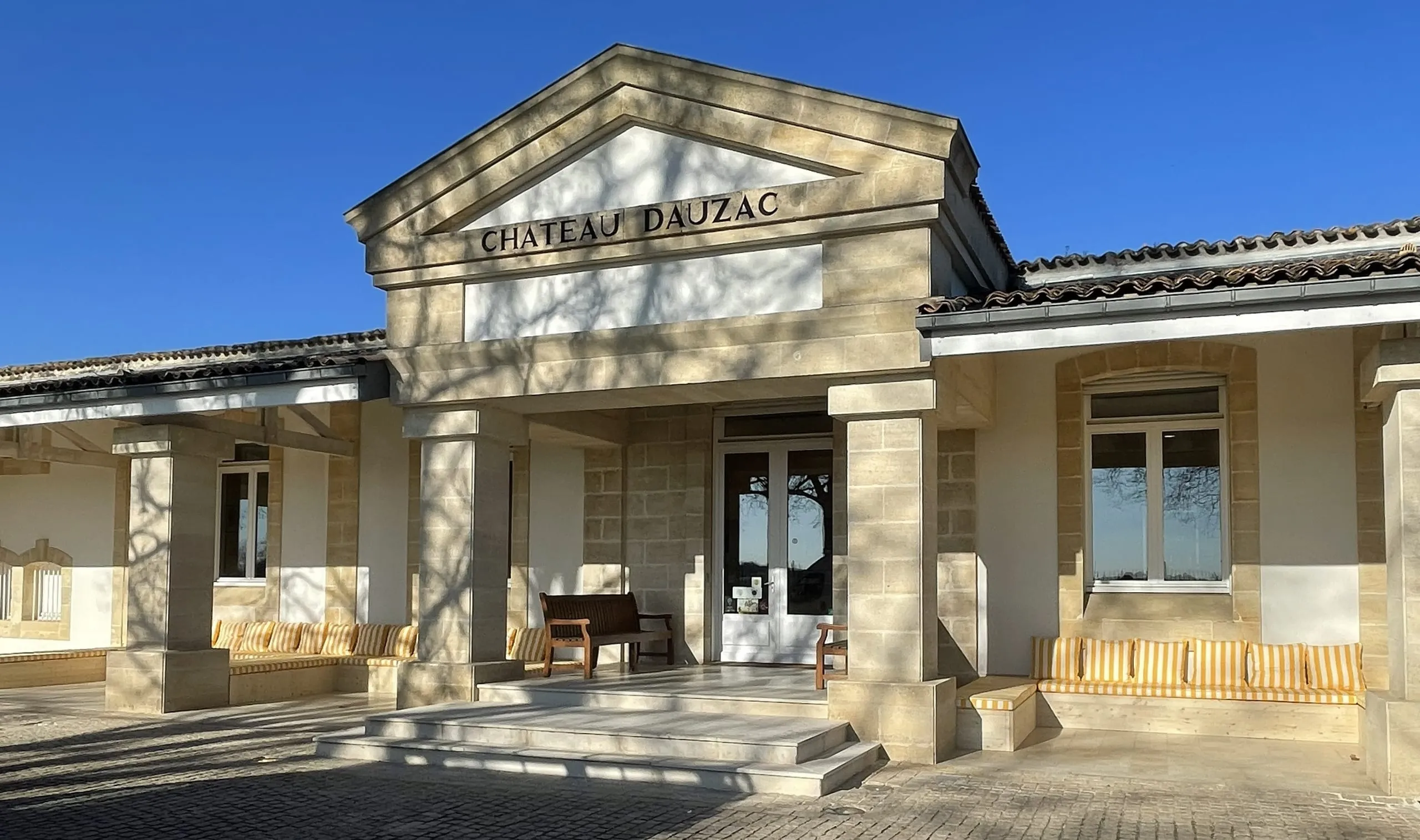 Ensemble de banquettes en bois intégré sous les arcades d’une façade en pierre