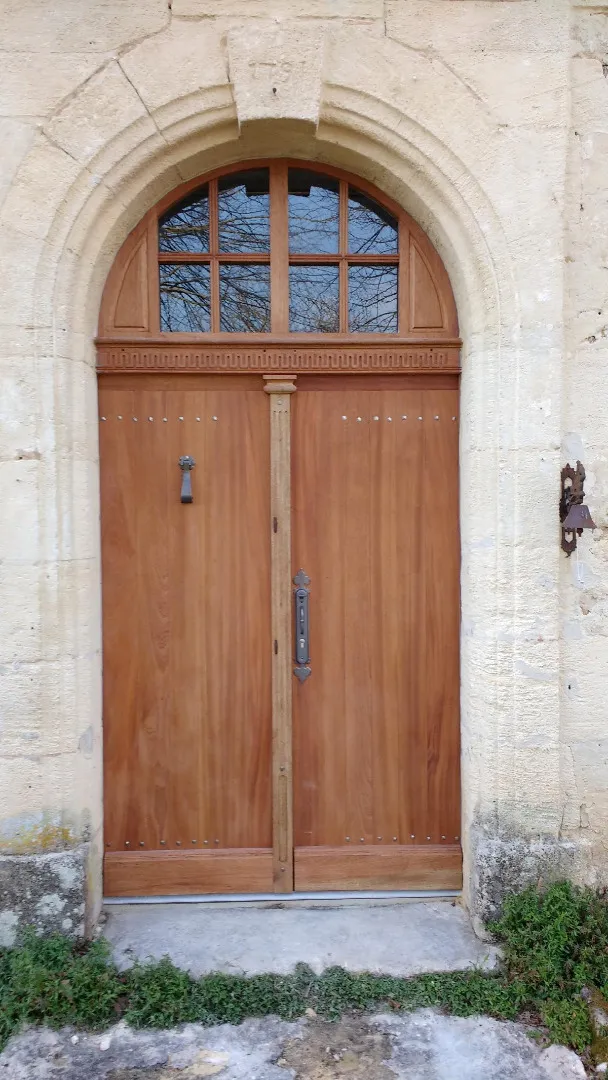 Porte d’entrée cintrée en bois fermée dans un encadrement en pierre
