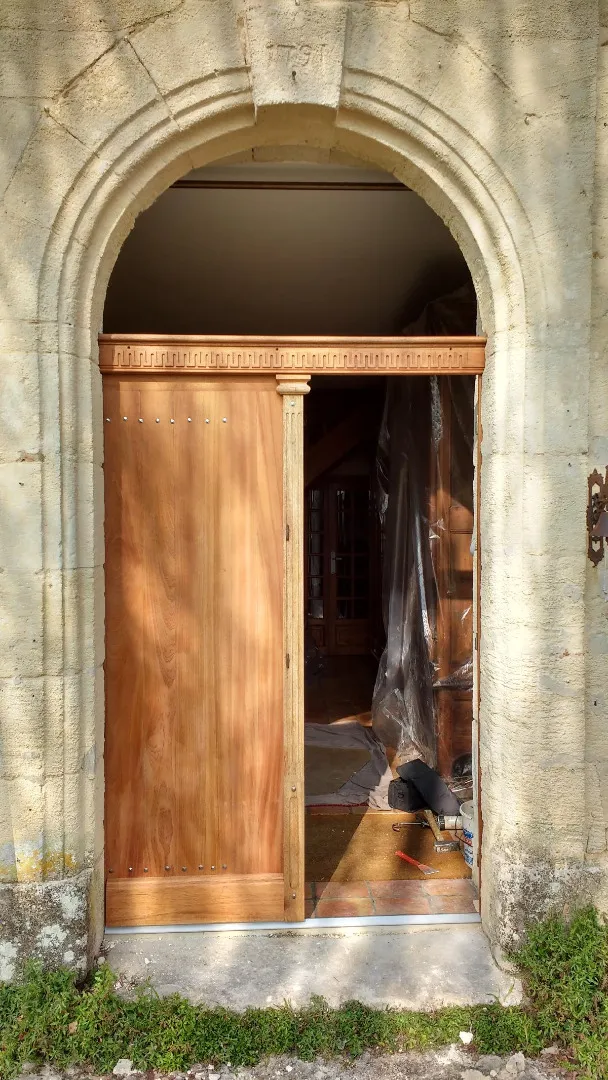 Porte d’entrée cintrée en bois avec un vantail ouvert