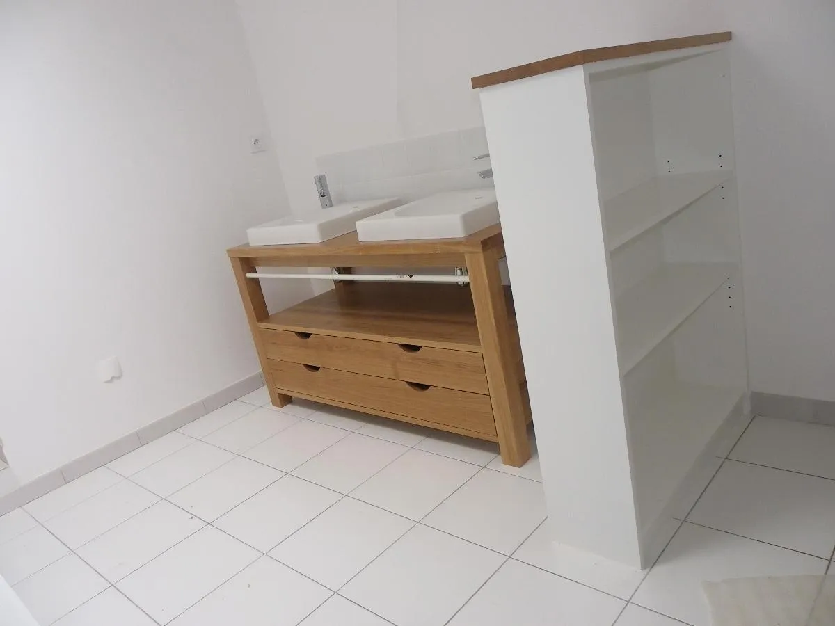 Meuble double vasque en bois installé entre deux rangements blancs